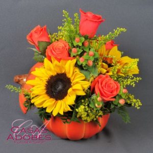 Orange roses and yellow sunflower in pumpkin