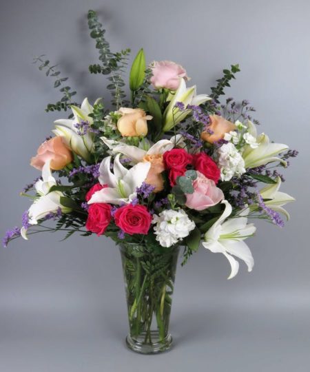 A vase beautifully arranged with fragrant white stock, white stargazer lilies, peach and hot pink roses accented with wonderful eucalyptus and misty. This bouquet is presented in a glass fluted vase and is sure to delight any occasion!