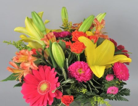 Make a summertime splash with a pop art mix of yellow lilies, set against a jumble of hot pink gerbera daisies, hot pink spray roses, orange spray roses, and orange alstroemeria presented in a modern glass cube vase!