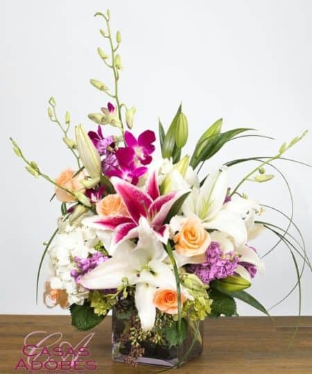 Make their day absolutely memorable with this bouquet filled with fragrant stargazer lilies in pink and white,  peach roses,  lavender stock, purple dendrobium orchids and tropical foliage. This design is filled with fragrance and presented in large cube vase lined with ti leaves.
