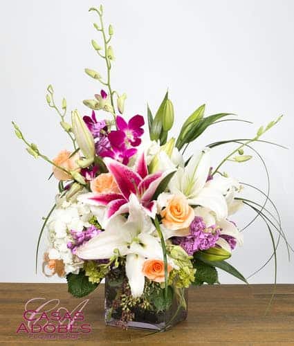 Make their day absolutely memorable with this bouquet filled with fragrant stargazer lilies in pink and white, peach roses, lavender stock, purple dendrobium orchids and tropical foliage. This design is filled with fragrance and presented in large cube vase lined with ti leaves.