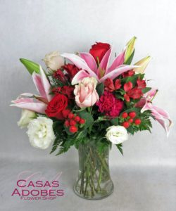 This luxe arrangement includes stargazer lilies, pink roses, red roses, red alstroemeria, maroon carnations, red coffee berries and white lisianthus with fresh lush greenery.