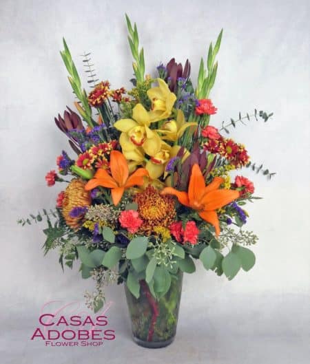 Glowing and gorgeous. Bring harvest colors into the home with an arrangement made with the freshest blooms. Our bouquet features an exquisite yellow cymbidium orchid with fall colored daisies, bronze spider chrysanthemums, orange lilies, safari sunsets, orange miniature carnations, orange gladiolas, and fragrant seeded eucalyptus. 