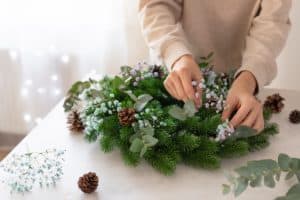 female hands making a Christmas wreath with flowers. Christmas decor self made. copy space
